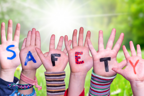 Children's hands in the air with "safety" written on their hands