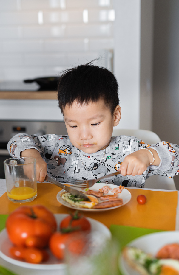 Photo of a young boy sitting at a kitchen table eating a healthy meal